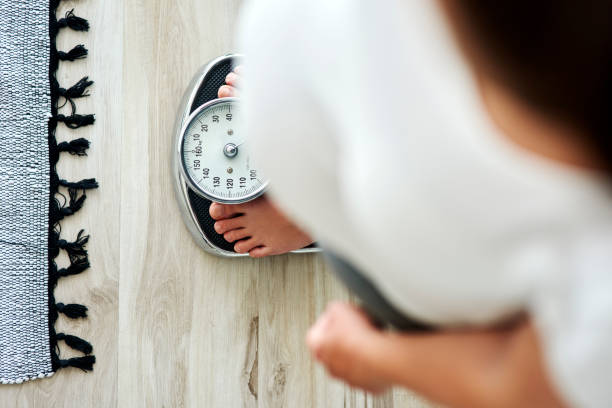 Potret seseoarang sedang menimbang berat badan nya